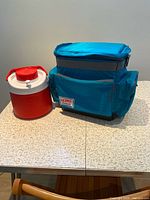 Thermos beverage jug beside Kooltote cooler closed