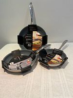 All three Zwilling fry pans nested, showing packaging and stainless handles