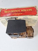 Brown glass REO Depot Wagon decanter with black roof next to original Tailwinds box