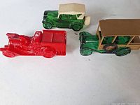 Three vehicle-shaped decanters: red roadster, green touring car with cream roof, green woody wagon