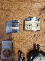 Five rectangular chrome lighters and partial view of straight razor and stopwatch