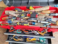 Toolbox open showing large quantity of screwdrivers and top view of drawer with pliers