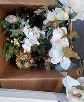 Box containing assorted artificial flowers and greenery
