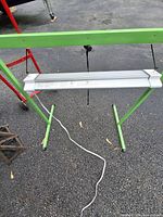 Full view of green stand with suspended silver grow light and power cord