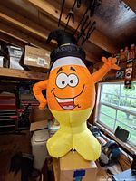 Front view of candy corn inflatable standing on box inside workshop