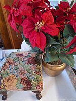 Artificial poinsettia and tapestry footstool visible in background; none are part of lot