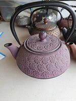 Full view of plum cast iron teapot with lid and handle