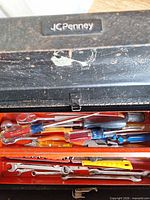 Closed JCPenney black toolbox with view of upper tray containing screwdrivers and wrenches