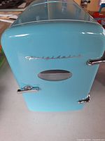 Front view of blue Frigidaire mini fridge showing logo and chrome handles