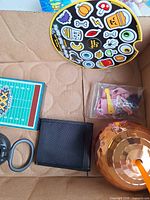 Items grouped inside box: sticker sheet, notepad, card holder, toy container, ring handle, doll utensils