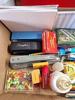 Box of notebooks, staplers, push pins and miscellaneous desk items