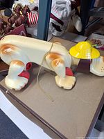Side view of plastic pull toy dog showing color, wheels and hat