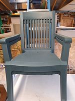 Front view of one dark green plastic patio armchair showing slatted back and seat