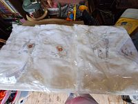 Three sealed baptism blankets on table in plastic wrap