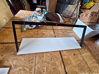 Modern metal frame shelf and bag of plastic items on table
