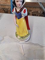 Front view of larger Schmid Snow White figurine with broken arm piece on tissue