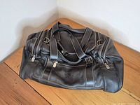 Front view of black leather Roots weekender bag showing overall design and condition