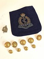 Group shot of nine brass buttons, cap badge, and embroidered pocket patch