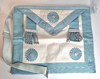 Full view of apron front showing trim, flap, rosettes, tassels, and belt