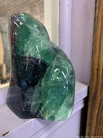 Freeform green and purple art glass paperweight displayed upright