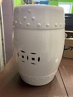 Side view of white ceramic garden seat showing raised bosses and cut-outs