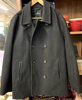 Front view of black London Fog pea coat showing double-breasted button layout and pockets