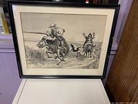 Framed ink drawing of two cowboys on horseback displayed upright