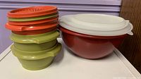 Stacked green bowls with red/orange lids beside red mixing bowl with white lid