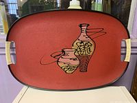 Front view of red MCM serving tray showing graphic, rim and handles