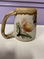 Side view of stoneware mug showing floral decoration and handle