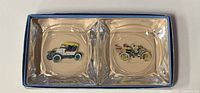 Open presentation box showing two antique car themed glass ashtrays