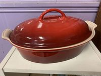 Red Le Creuset oval Dutch oven with lid, side view