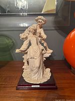 Front view of entire Capodimonte courting couple figurine on wooden base