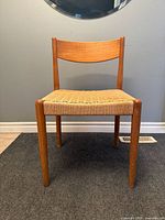Front view of teak side chair showing curved backrest and woven seat