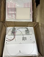 Top view into box showing one LED troffer with wiring harnesses and protective foam