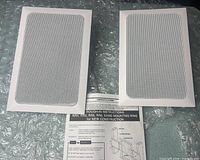 Front view of both speaker grilles on bubble wrap with instruction sheet