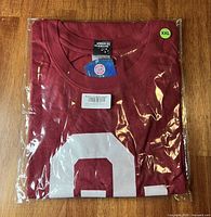 T-shirt folded in original plastic with size sticker and tags visible