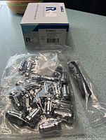 Bag of chrome lug nuts and adapter key beside boxed kit
