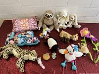 All items layout on red cloth including pillows and assorted plush toys