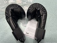 Pair of black UFC youth gloves removed from bag