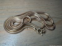 Coiled snake chain necklace on wood surface