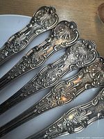 Five ornate fork handles showing engraved pattern