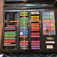 Open art case showing oil pastels, watercolor cakes and accessories