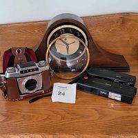 Group shot showing all items: Ihagee camera in case, Techron mantel clock, loose glass cover, Kodak camera, Vivitar LF camera