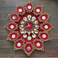 Front view of ornate gold gilded wall clock with red velvet and mirrors