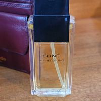 Sung Alfred Sung eau de toilette bottle next to wallet