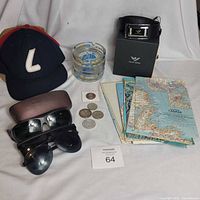 Group view of belt in box, caps, sunglasses, coin set, maps, souvenir glass