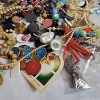 Overall pile showing faux pearls, gold beads, red tassel and mixed components