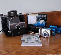 Overall lot with Polaroid camera, Canon PowerShot, two Nikon Coolpix cameras, Nikon box and software disc