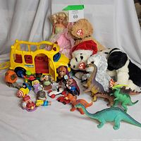 Group shot of Barbie, three Beanie Babies, school bus, dinosaurs, McDonald’s toys